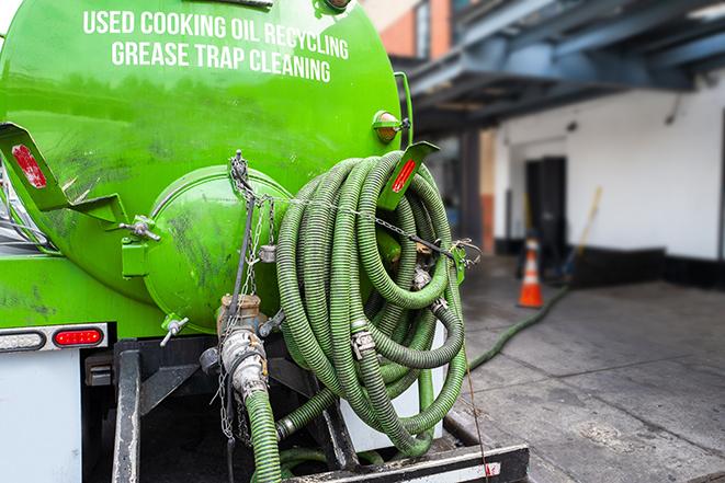 worker pumping grease trap at commercial kitchen in Greenock